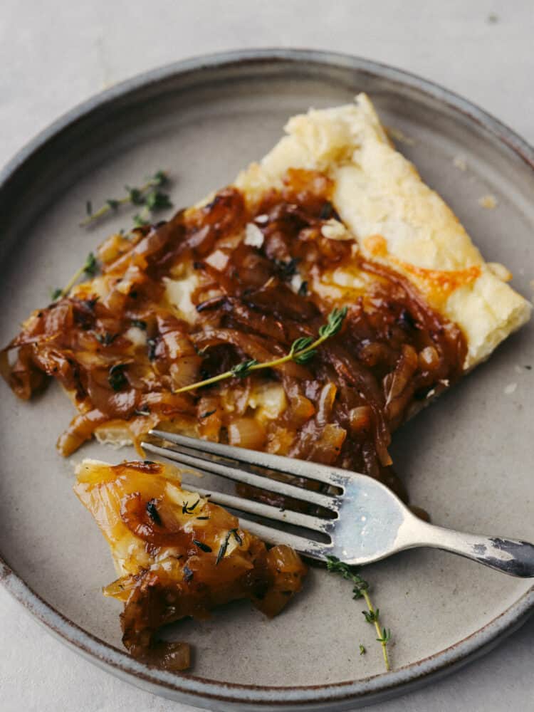 A slice of onion tart on a flate with a silver fork. 