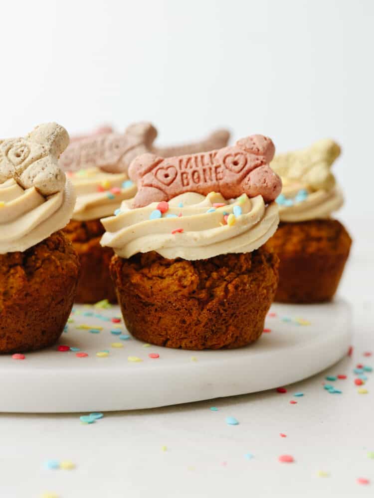 Multiple frosted pupcakes on a cake board.