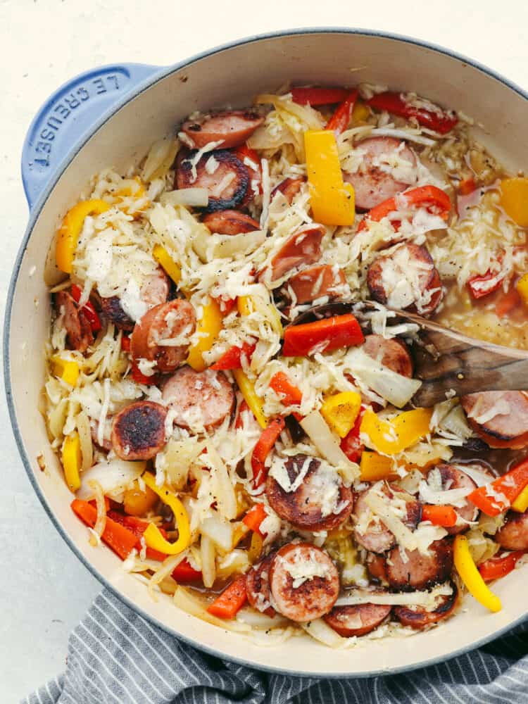 Kielbasa and sauerkraut cooket in a skillet on the stove. 