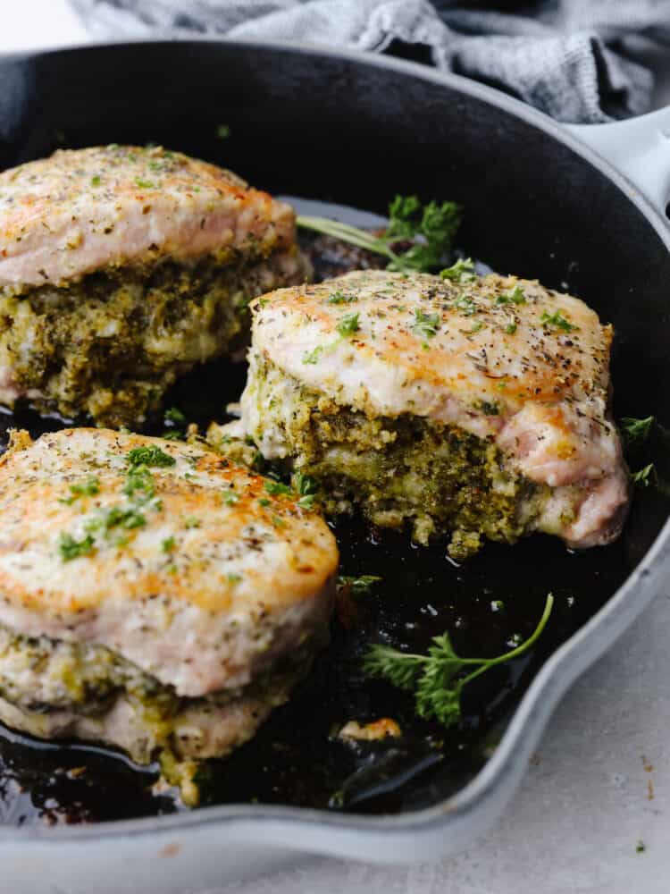 3 stuffed pork chops getting browned in a skillet. 