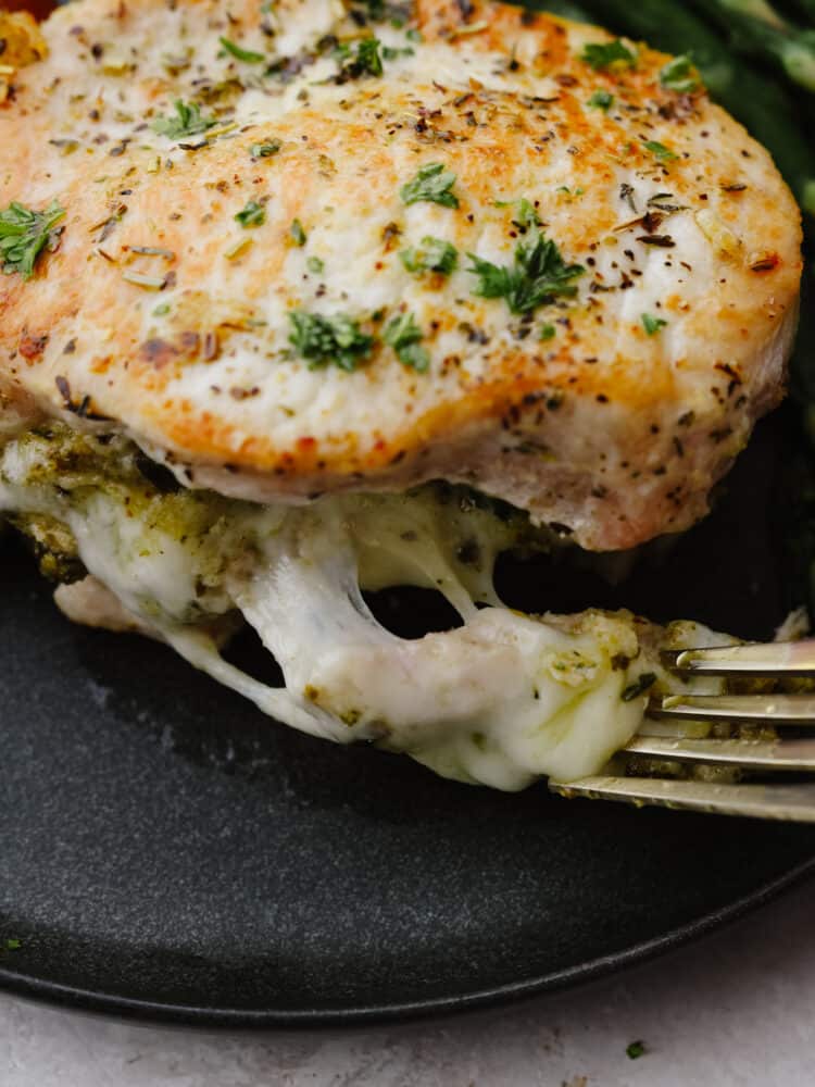 A close up shot of a fork cutting into a stuffed pork chop. 