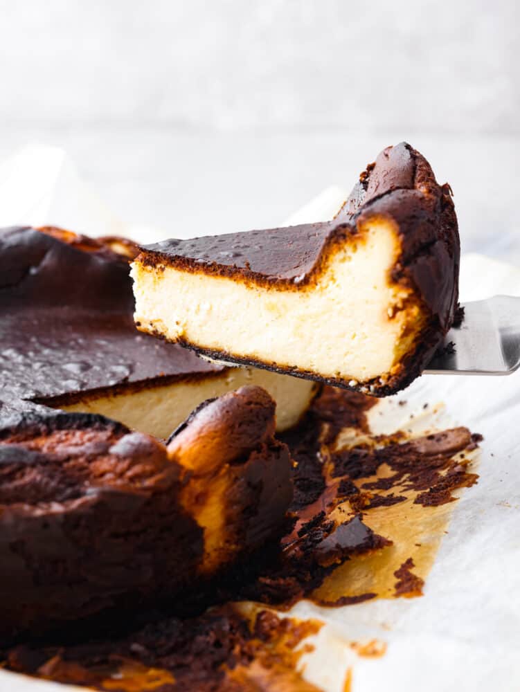 Side view of a slice of cheesecake being lifted away from the cheesecake.