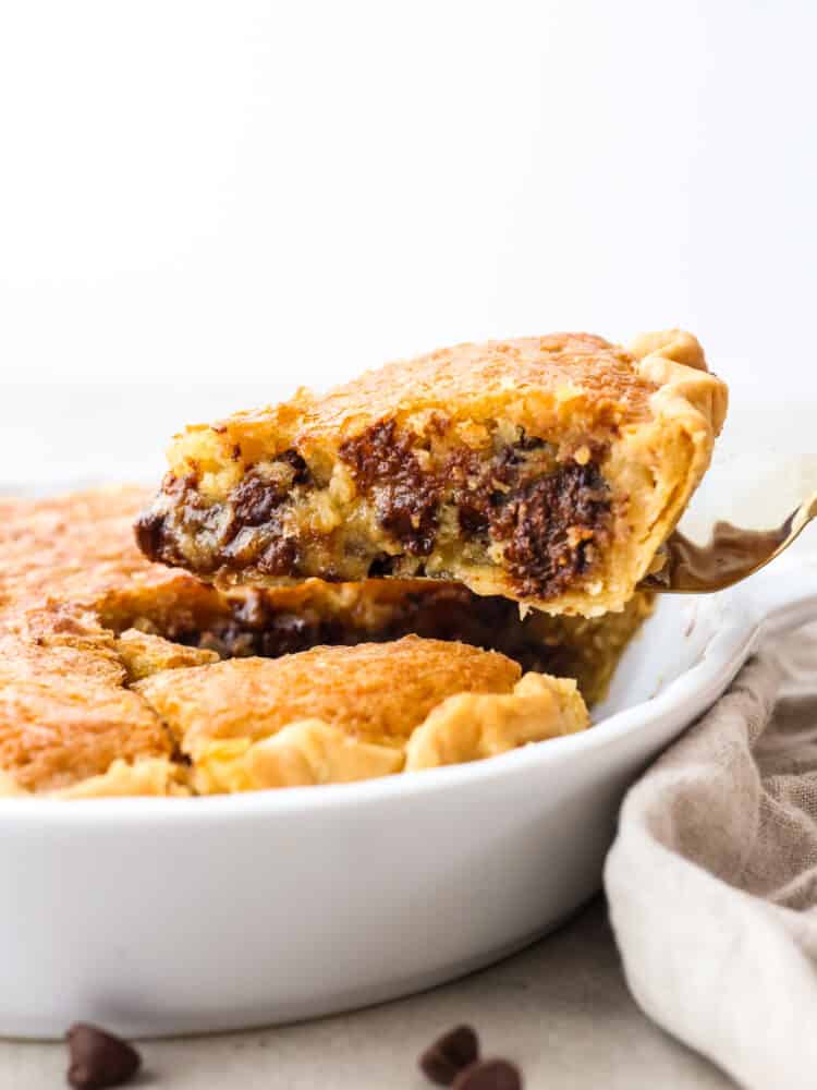 A slice of chocolate chip cookie pie being lifted out of a pan.