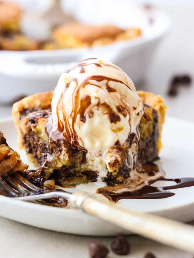 Front view of chocolate cookie pie topped with vanilla ice cream. It has a bite taken out of it with a fork.