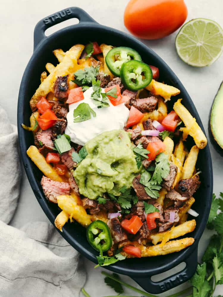 Top-down view of carne asada fries in a black serving dish.