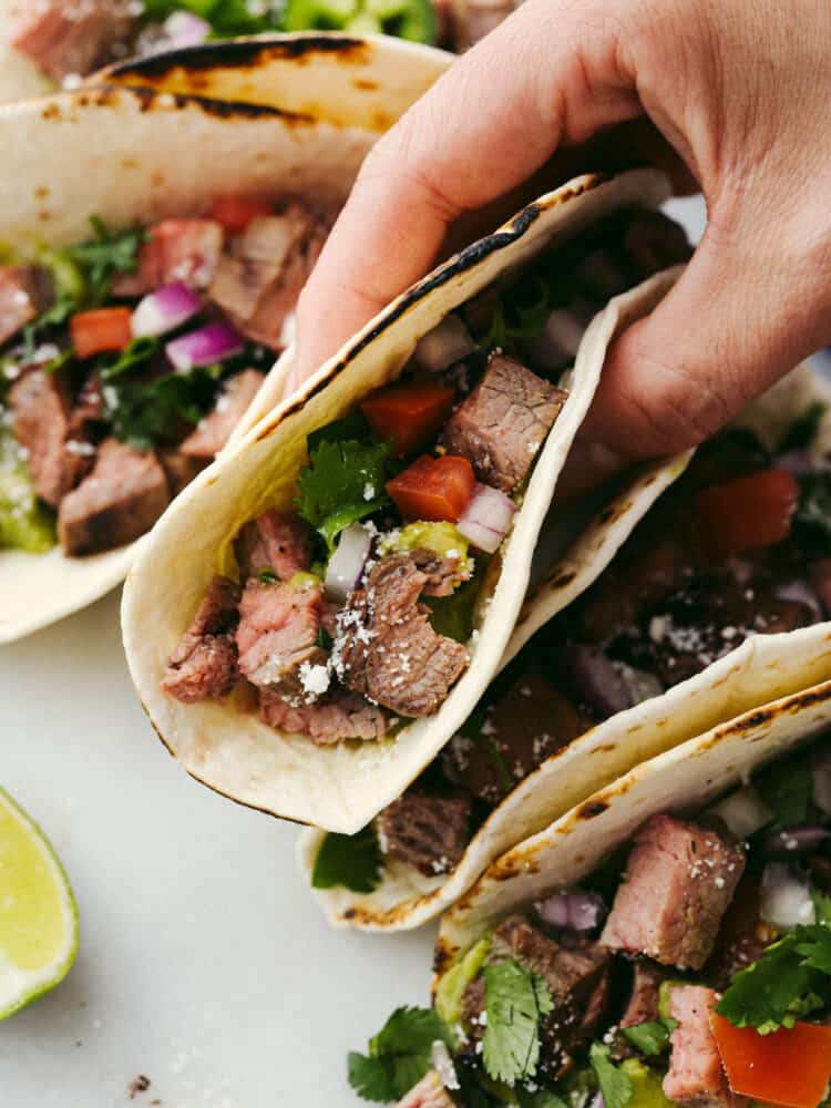 A carne asada taco folded in half and being held.