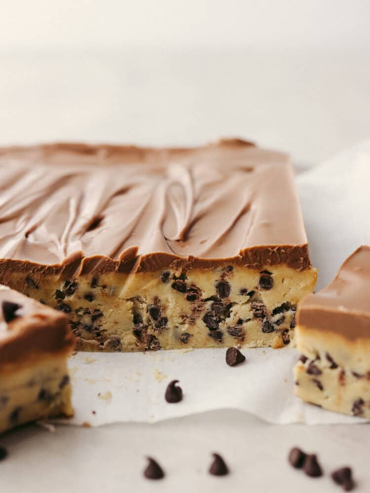 The side view of the chocolate chip cookie dough on parchment paper, ready to be cut. 