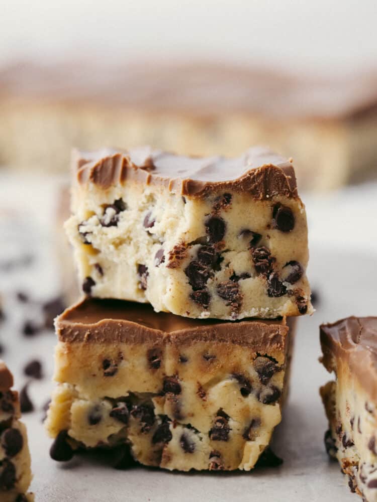 A stack of cookie dough bars, the top one has a bit taken out of it. 