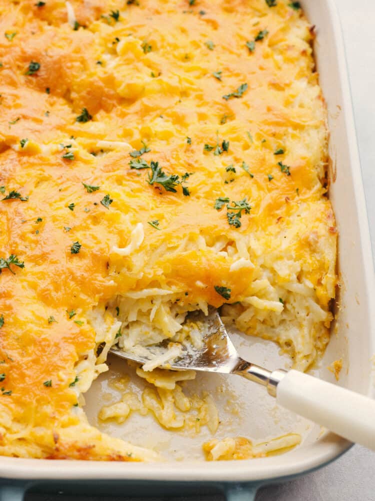 Closeup of a hashbrown casserole with a slice taken out of it.