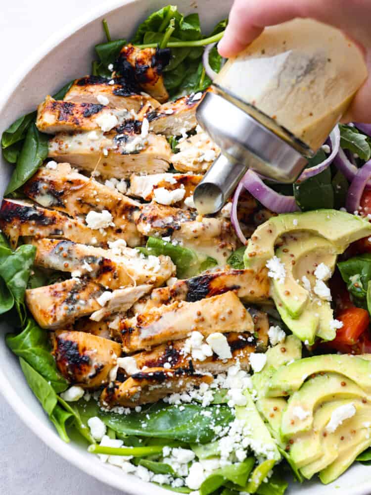 Honey mustard salad dressing being poured onto a salad. 