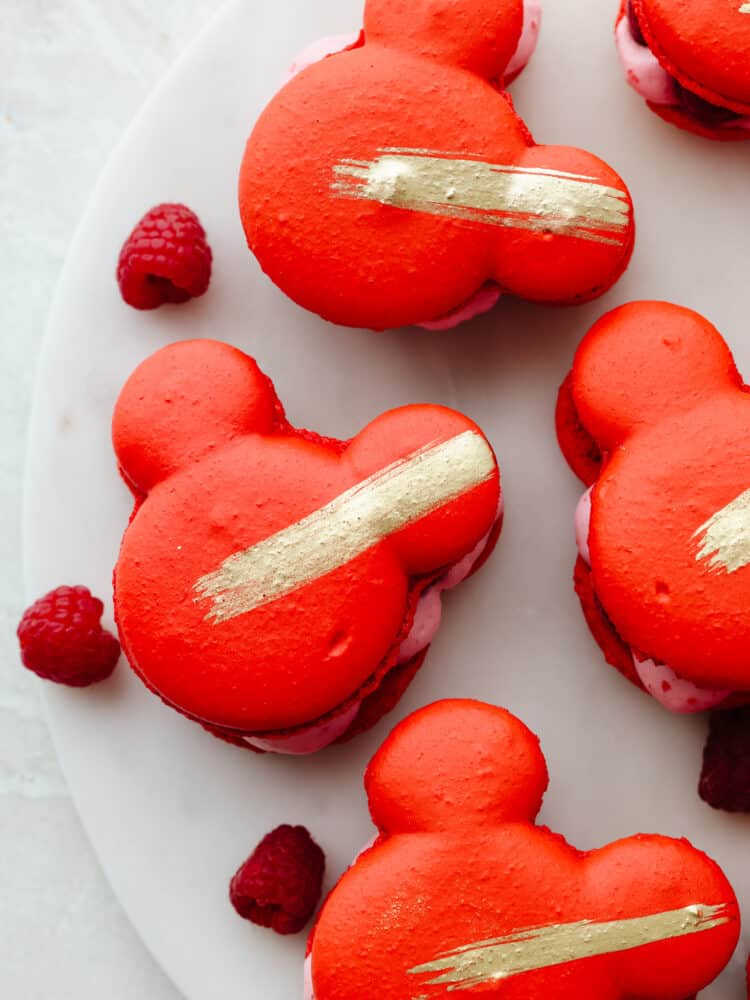 Top-down view of Mickey Mouse-shaped macarons on a white plate.