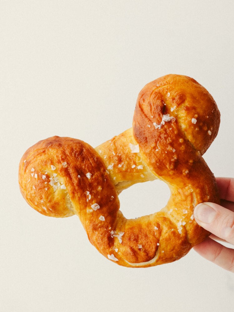 A closeup of a hand holding a Mickey pretzel. 