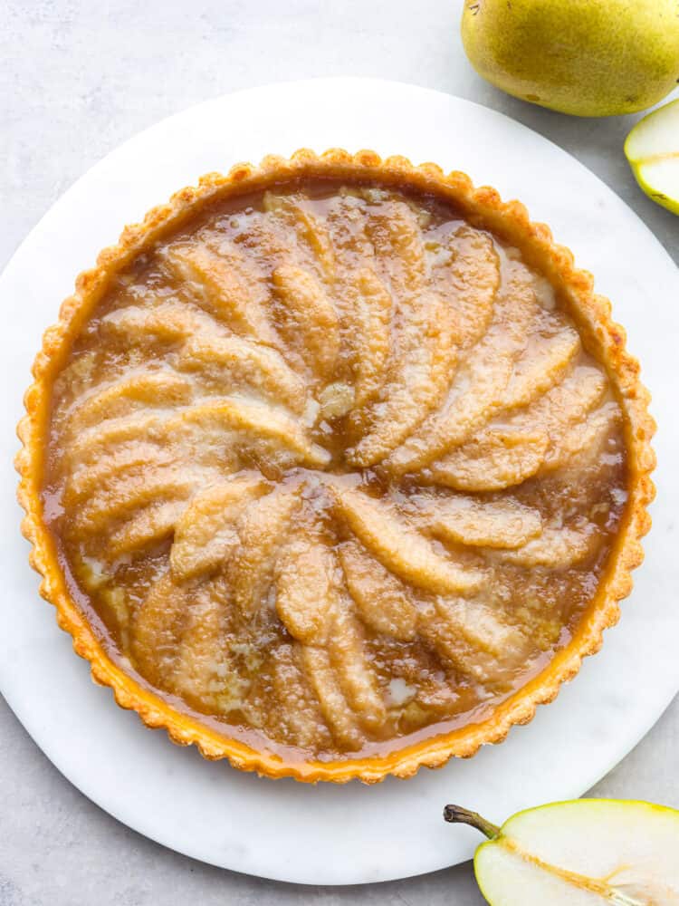 The top view of a pear tart on a white platter. 