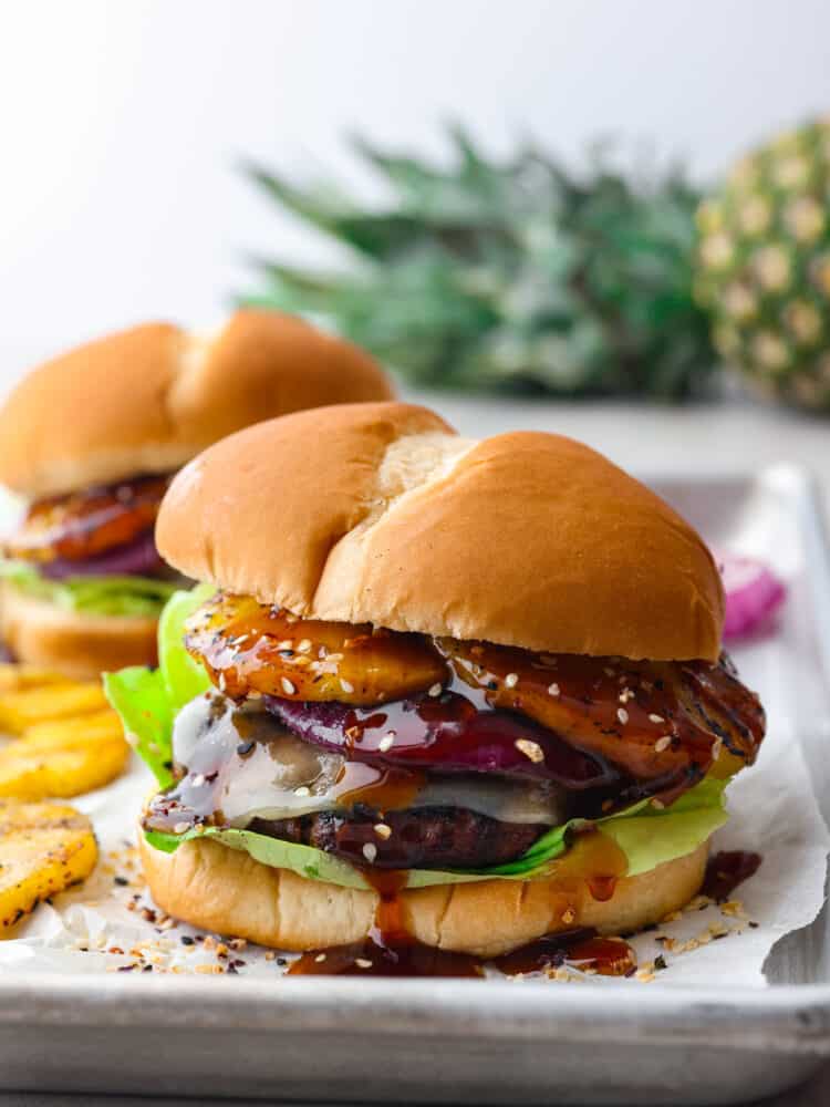 The side view of a teriyaki burger on a baking sheet with parchment paper. 