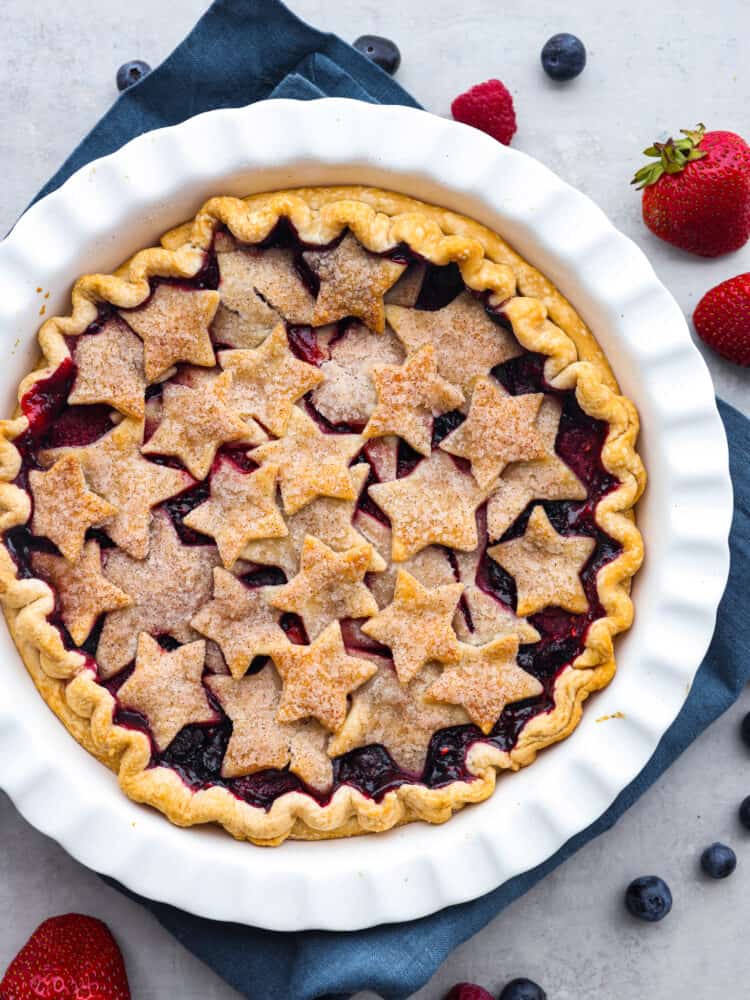 Top-down view of a triple berry pie in a white serving dish.