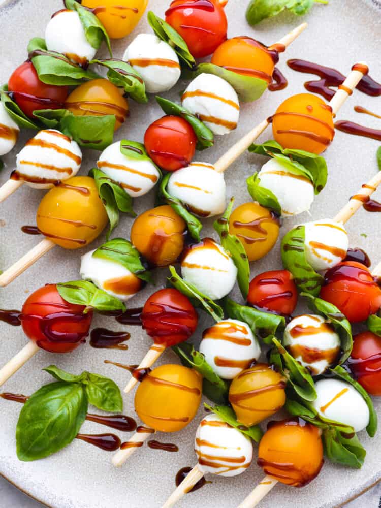 Caprese skewers drizzled with balsamic vinegar.