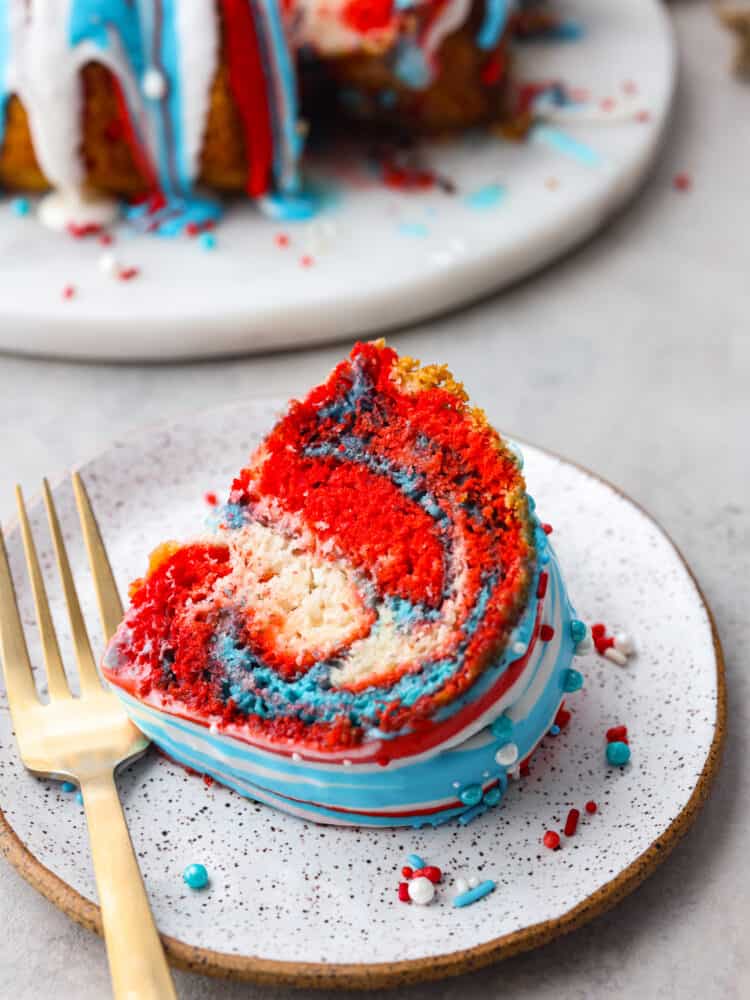 A slice of firework bundt cake on a plate with a gold fork. 