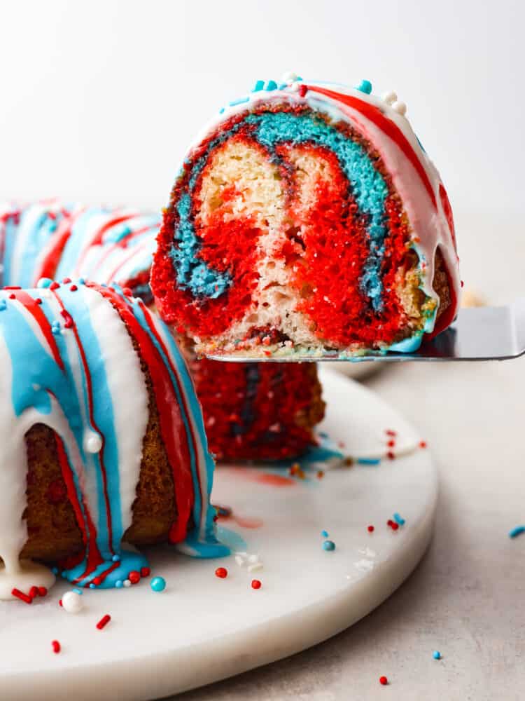 The side view of a slice of firework bundt cake being served on a silver cake server. 