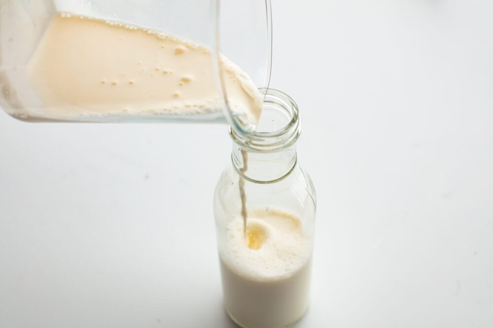 Half and half being poured into a glass jug. 