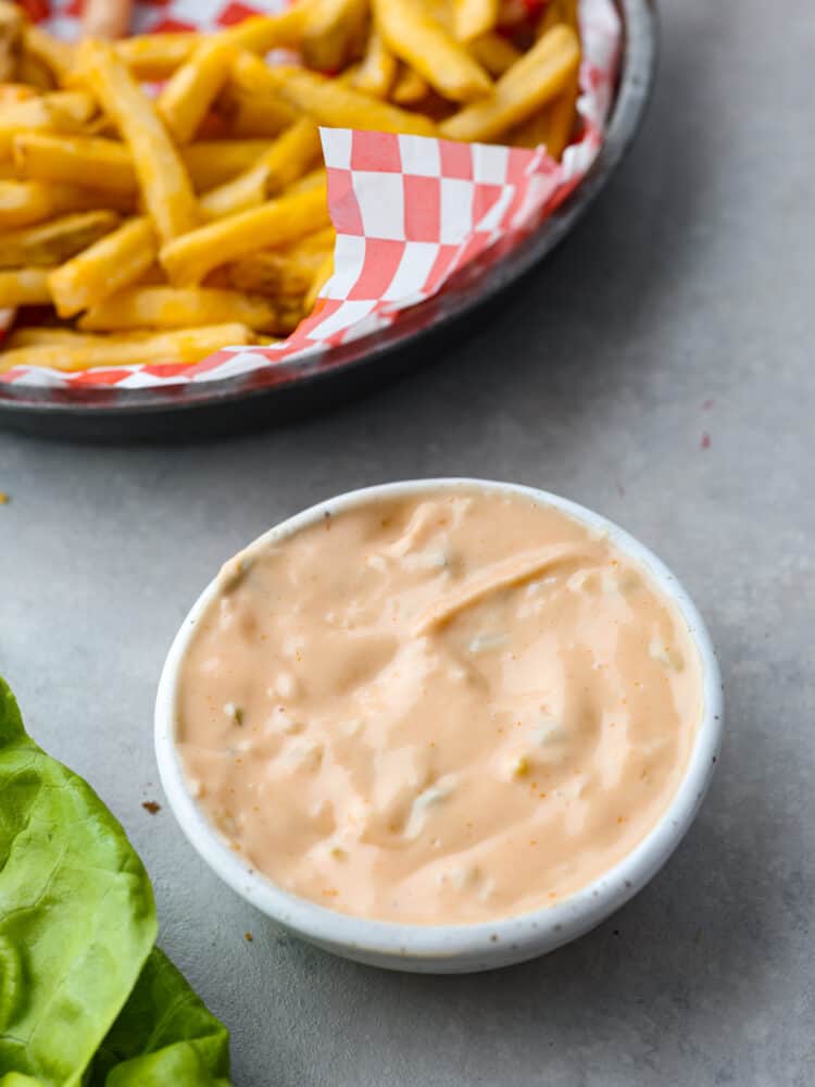 Overhead photo of In-N-Out sauce in a bowl with a side of fries and lettuce from a hamburger next to the bowl of sauce.