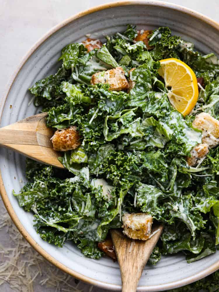 Top view of salad in a large gray bowl with wood serving spoons set inside the salad.