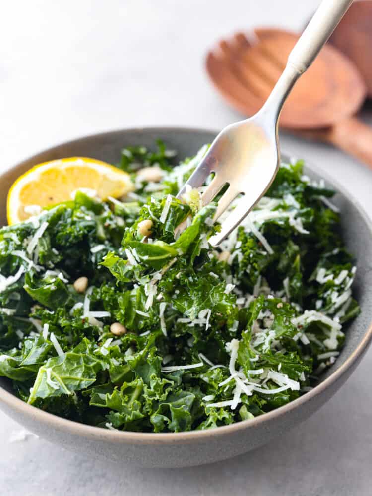 Closeup of a fork skewering a bite of lemon parmesan kale salad.