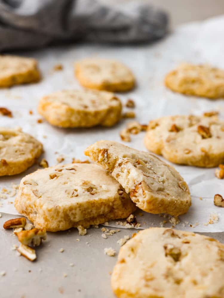 Pecan shortbread cookies stacked on another. The top one is broken in half to show what the inside looks like. 