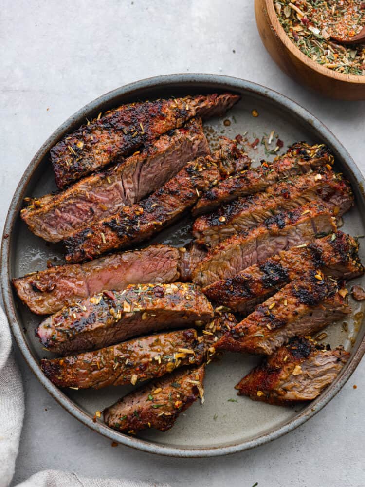 Cooked steak on a plate sliced and seasoned and ready to eat. 