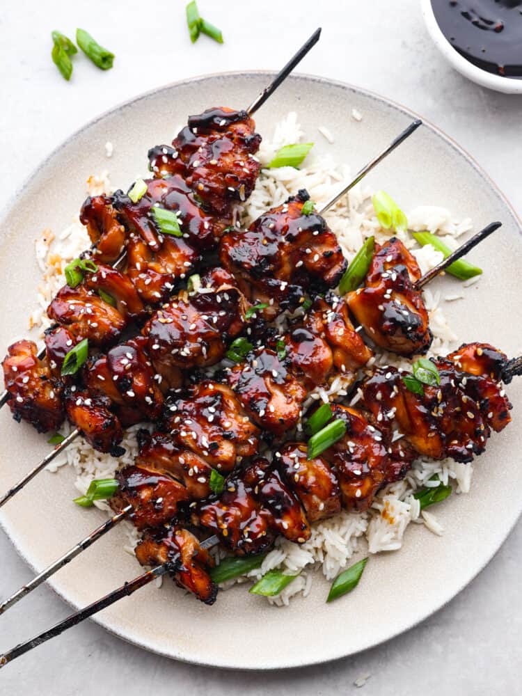 Top-down view of chicken skewers on a white plate.