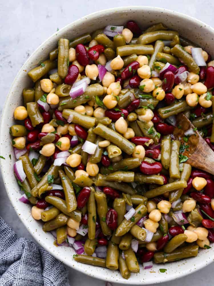 Top-down view of 3 bean salad in a white speckled bowl.