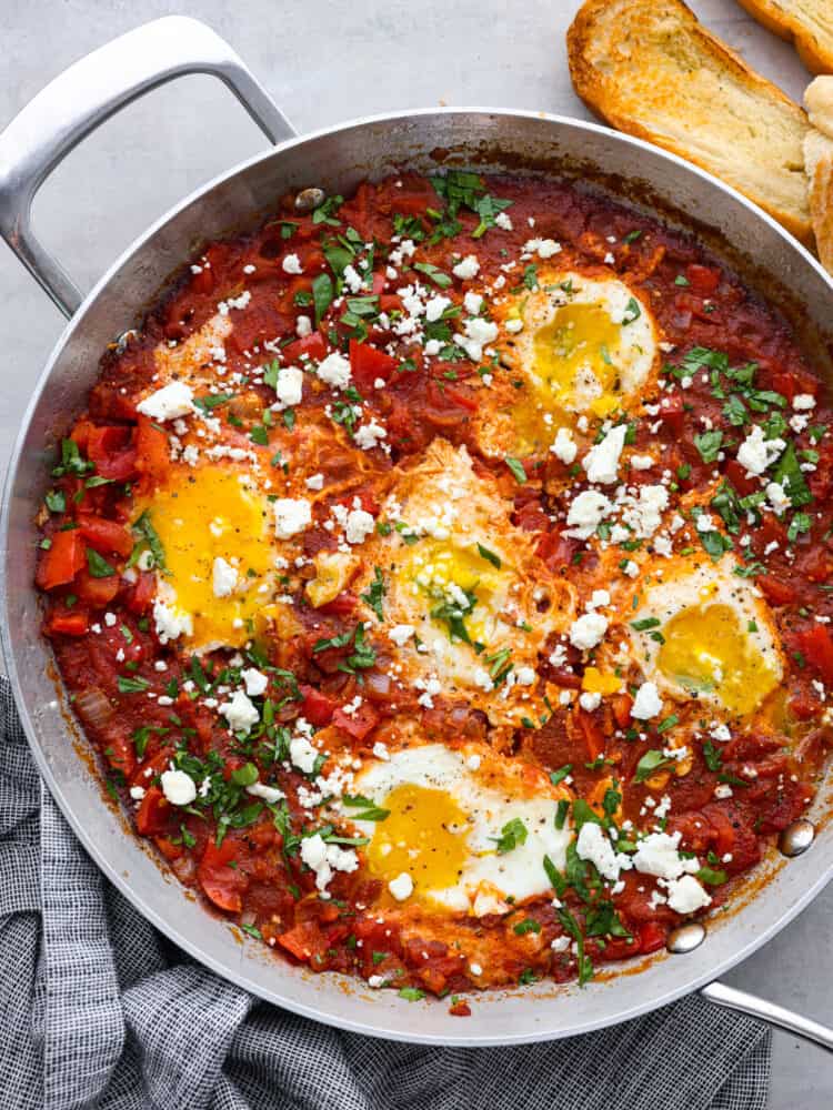 Top-down view of poached eggs and tomato sauce in a metal skillet.