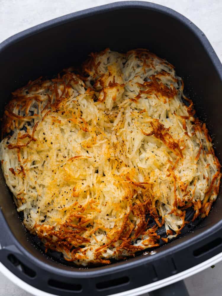 Top view of cooked hash browns in the air fryer basket.