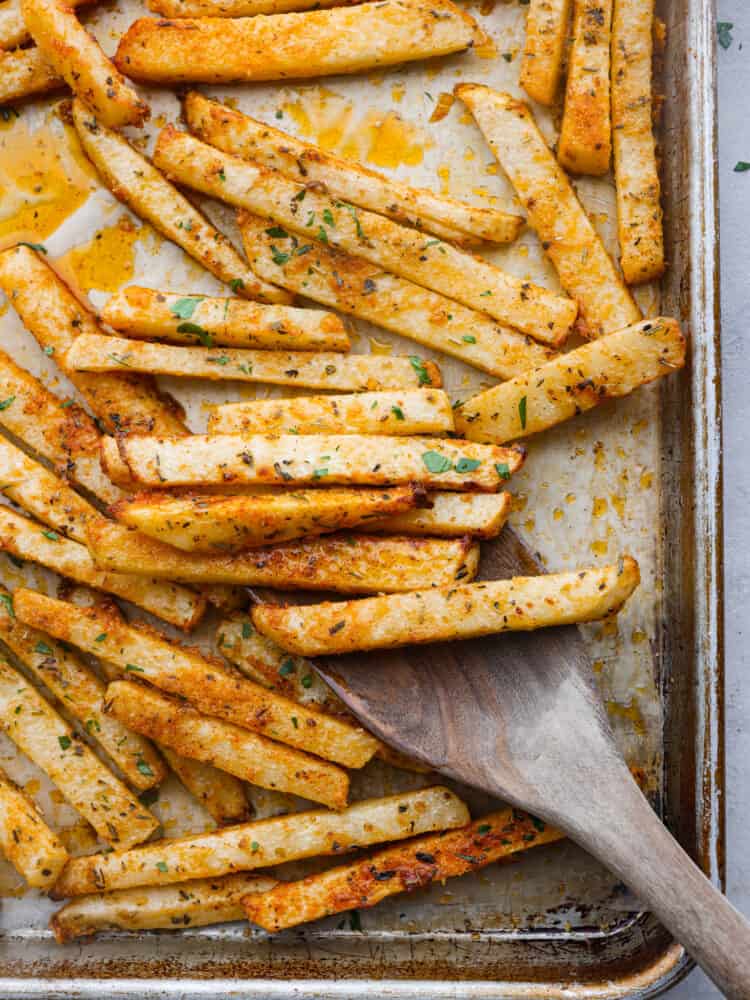 Top-down view of baked jicama fries on a baking sheet.