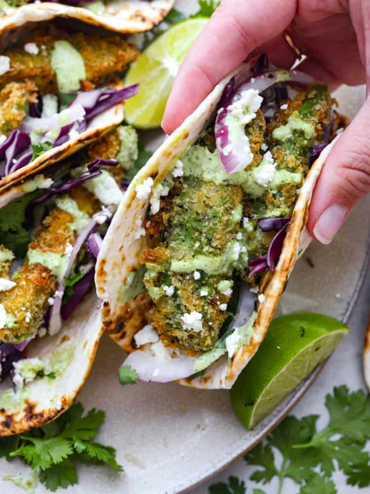 A fried avocado taco being picked up.