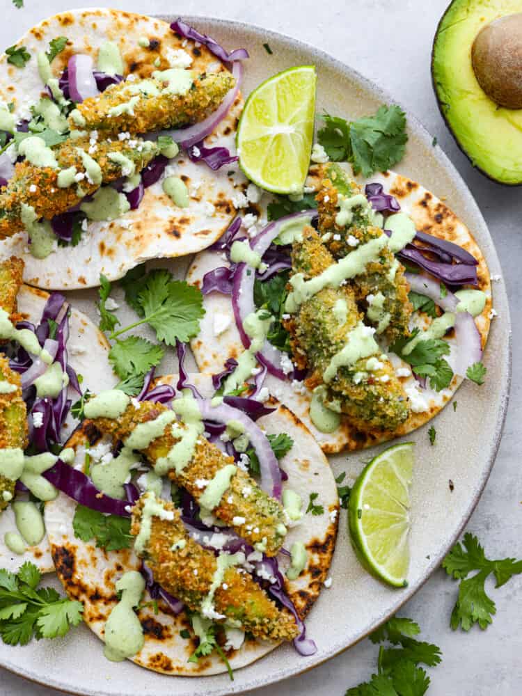 4 fried avocado tacos on a white plate.