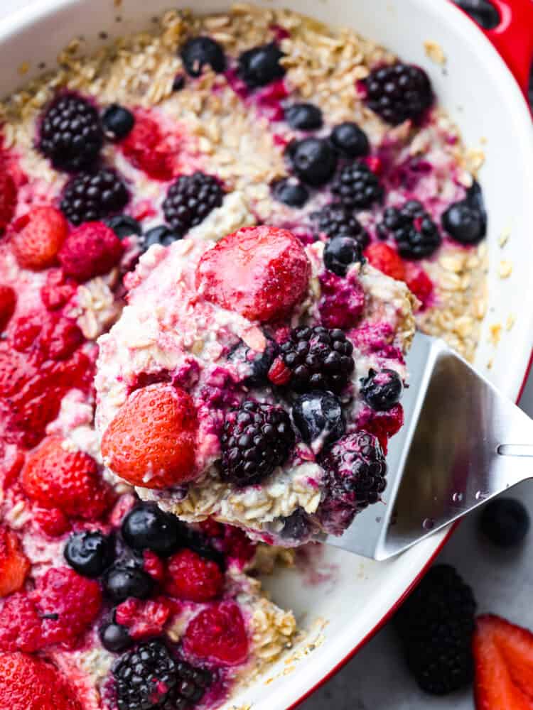 Closeup of berry oatmeal being scooped up with a metal spatula.