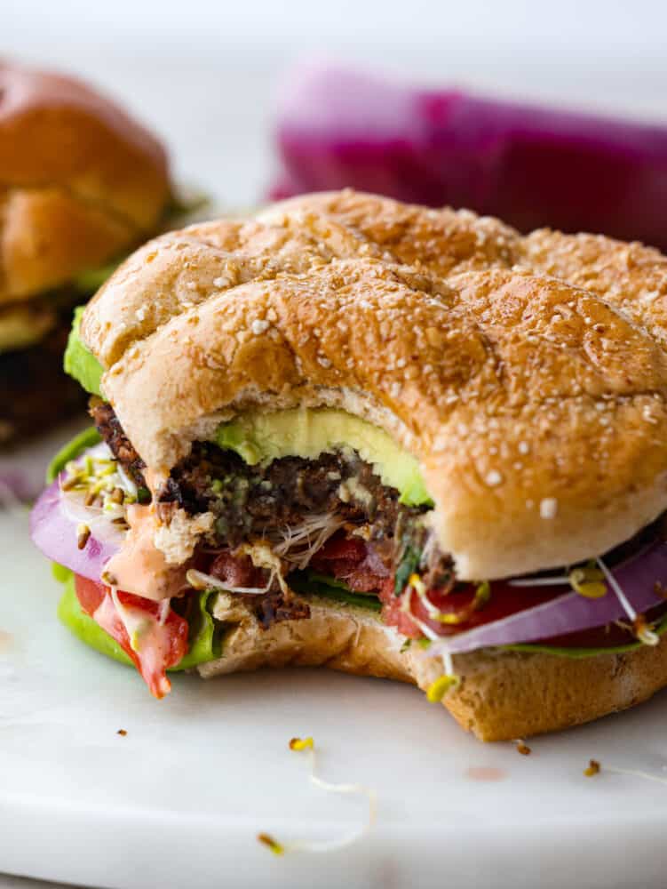 A close-up photo of an assembled black bean burger with a bite out of it.