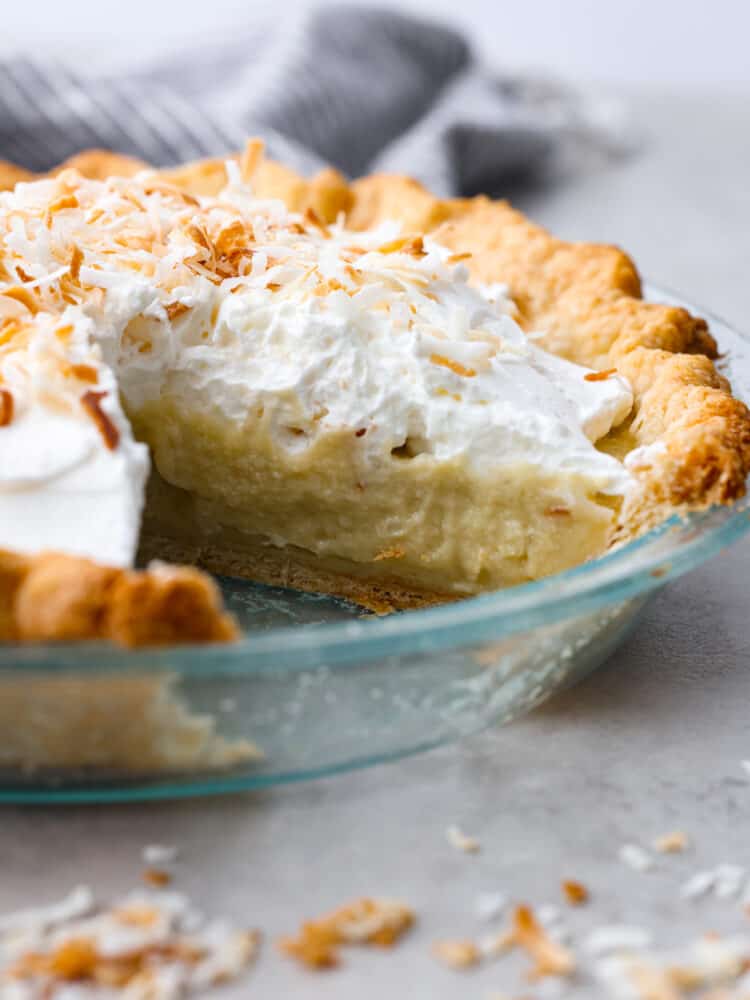 The side view of coconut cream pie with a slice taken out of the pie pan. 