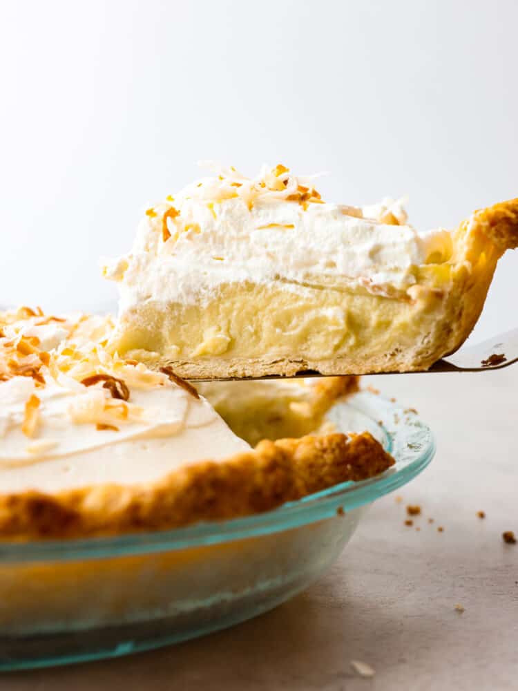 A slice of coconut cream pie being served from a pie dish.