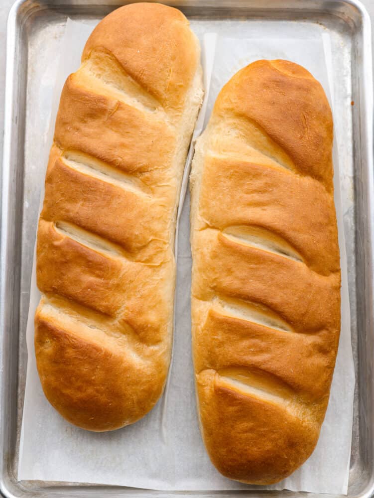 Top-down view of 2 French bread loaves on a baking sheet.