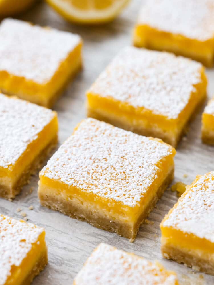 Lemon cheesecake bars cut into squares and sprinkled with powdered sugar. 