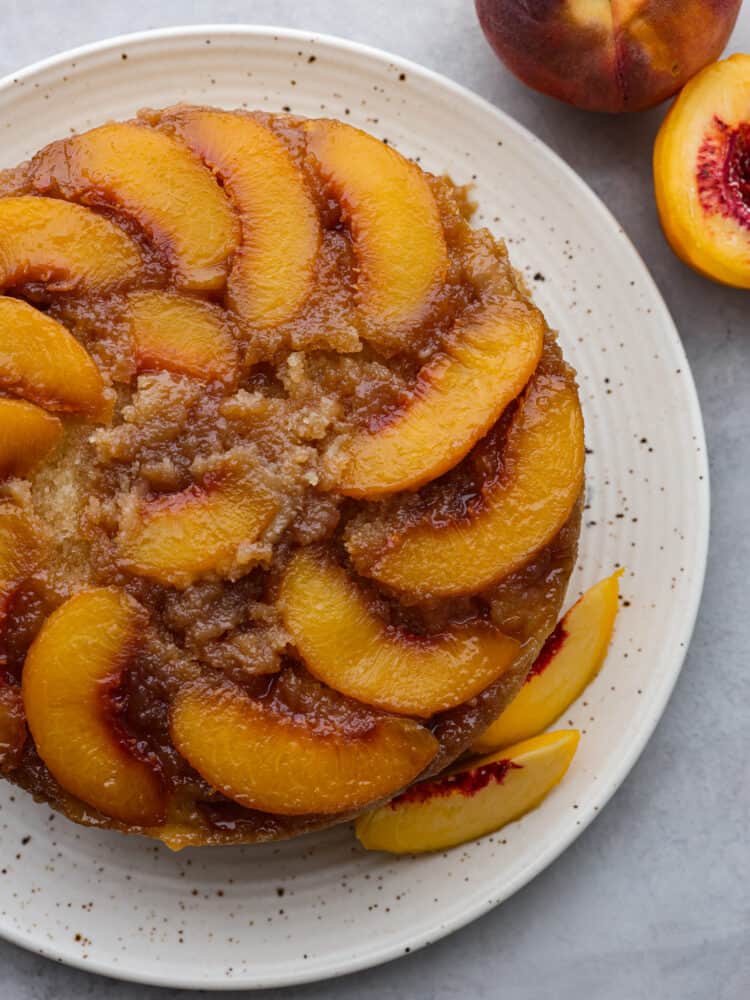 A peach upside down cake on a white speckled platter. 