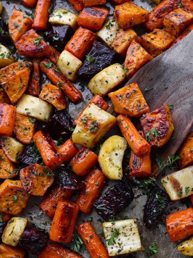 A close up of veggies being served with a wooden spoon. 