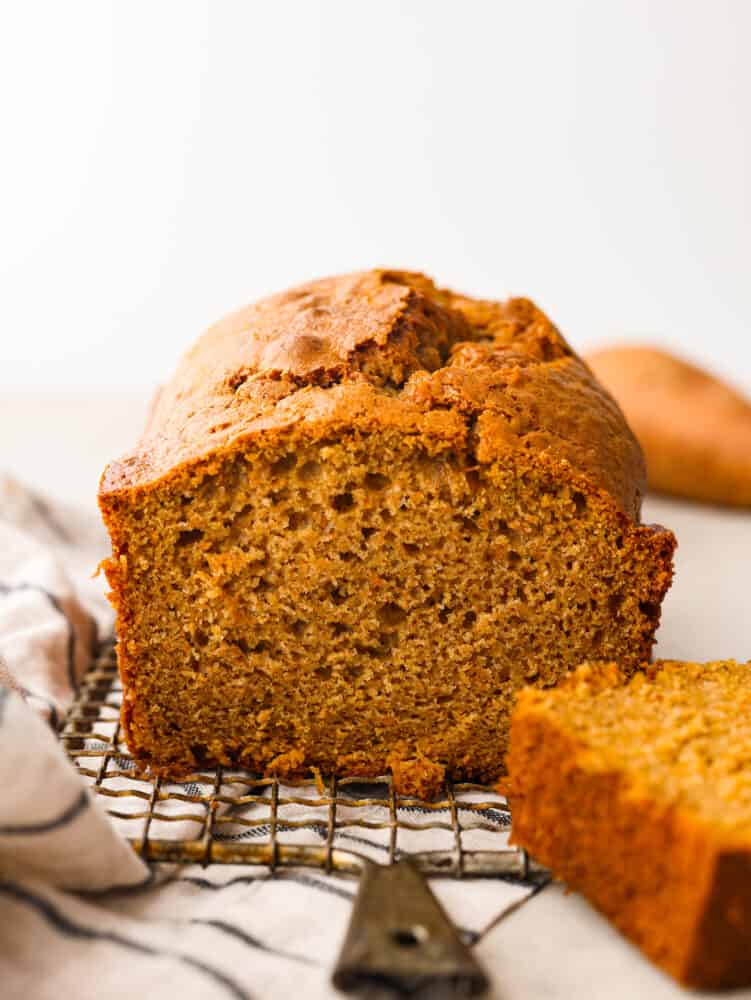 Front view of a loaf of sweet potato bread. A slice is cut out of it.