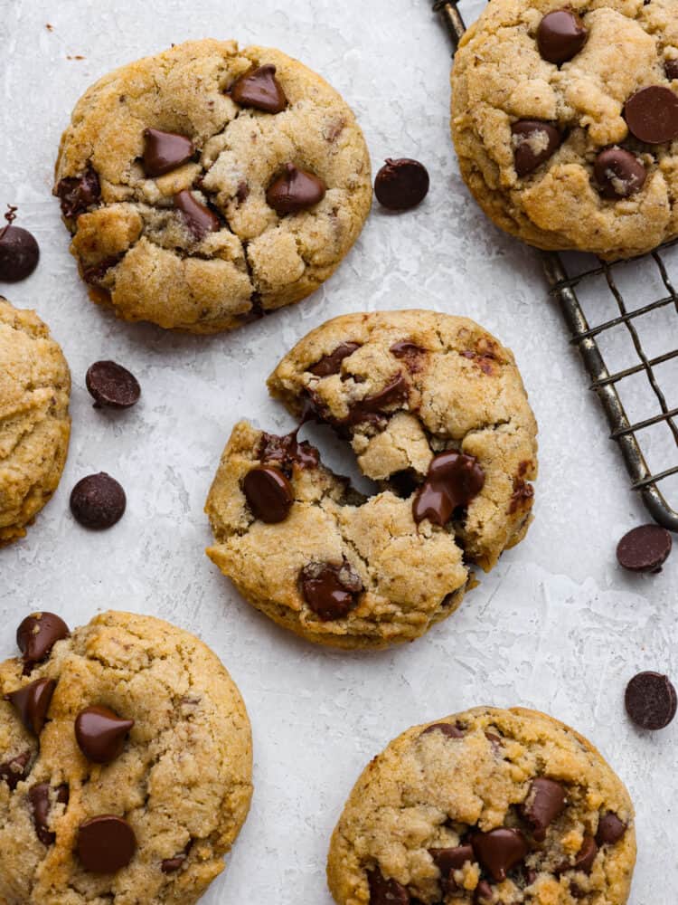 The top view of cookies on parchment paper. A cookie is broken in half showing the soft inside and melted chocolate. 