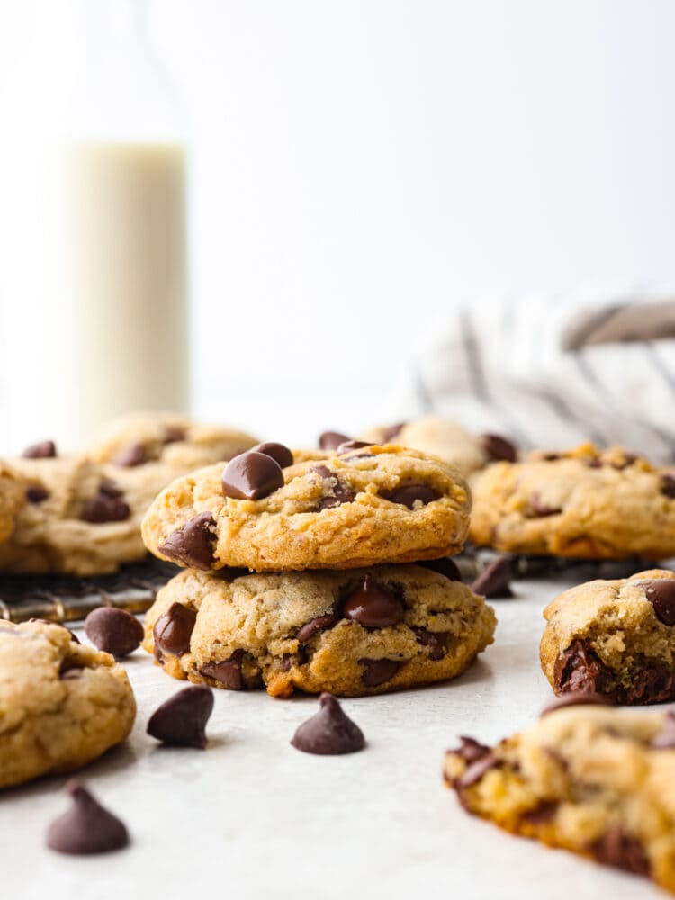 The side view of a stack of 2 chocolate chip cookies with other cookies surrounding them. 