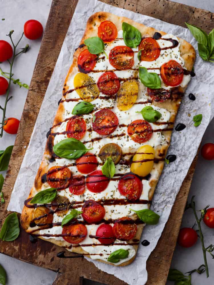 A full caprese flatbread on parchment paper.