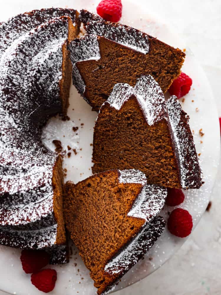 The top view of a chocolate pound cake on a cake stand with a few pieces sliced. 