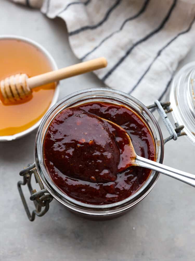 The top view of a jar of honey chipotle sauce with a silver spoon in it. 