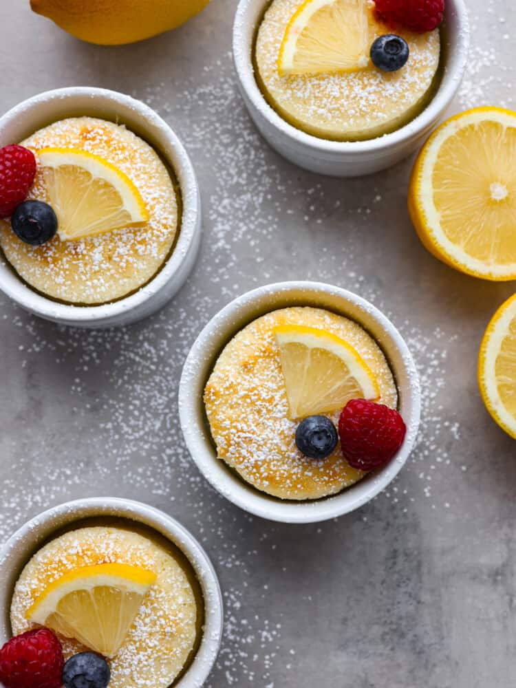 The top view of lemon pudding cake in 3 ramekins. Each dusted with powdered sugar and topped with berries. 